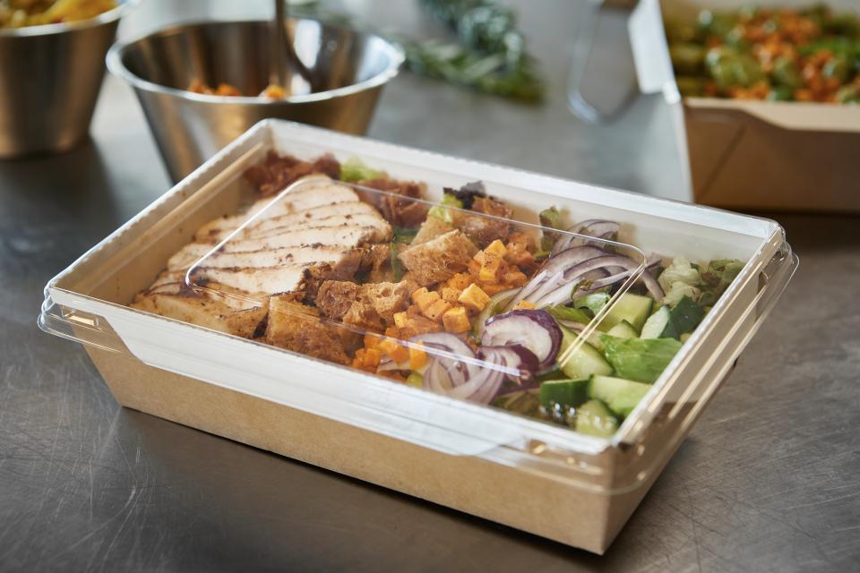 Takeawayemballagw i brunt pap og plastiklåg med salat